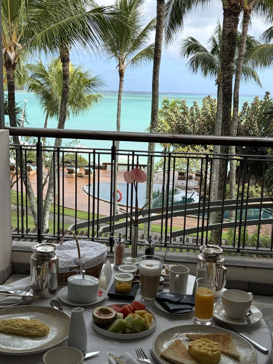 Private terrace breakfast service with palms, the pool and the turquoise bay beyond, Beachcomber Royal Palm