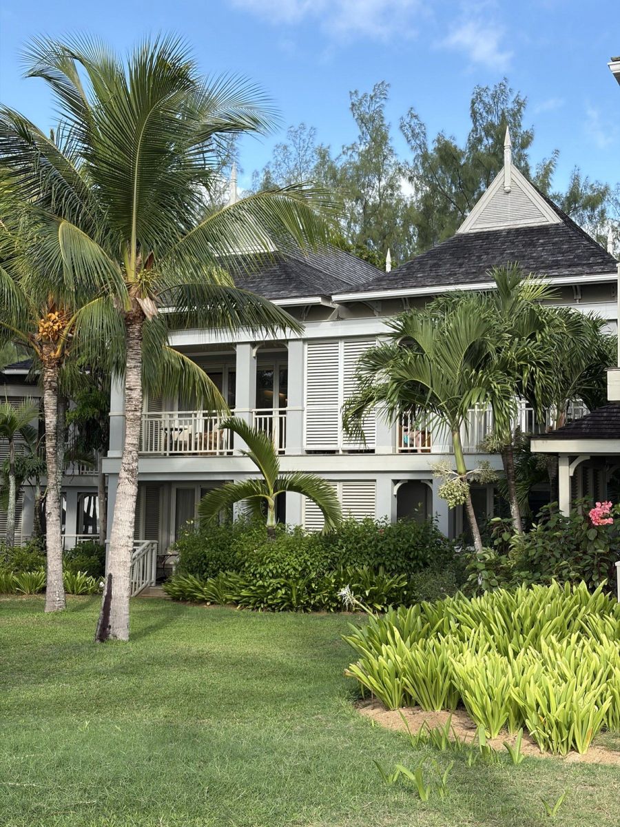Cream colonial-style villa with shutters, balconies and palm garden at St Regis Mauritius Resort at Le Morne