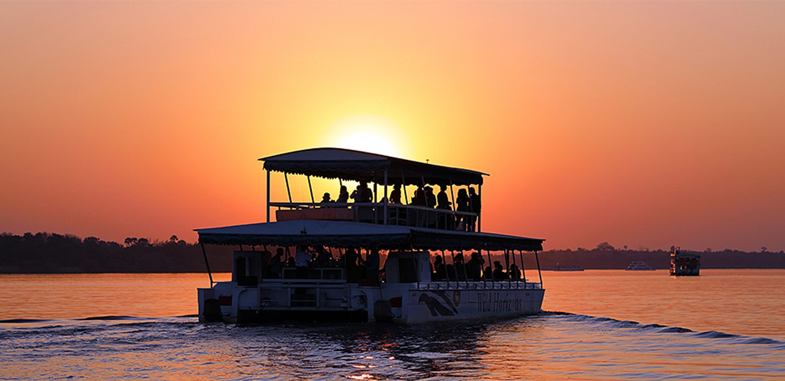 A boat cruise on the Zambezi River at sunset as the tourists on board enjoy sundowner cocktails.