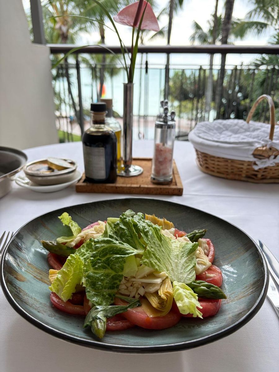 Salad of artichoke, tomato and asparagus on a private terrace at Beachcomber Royal Palm, with anthurium centerpiece and palm trees beyond
