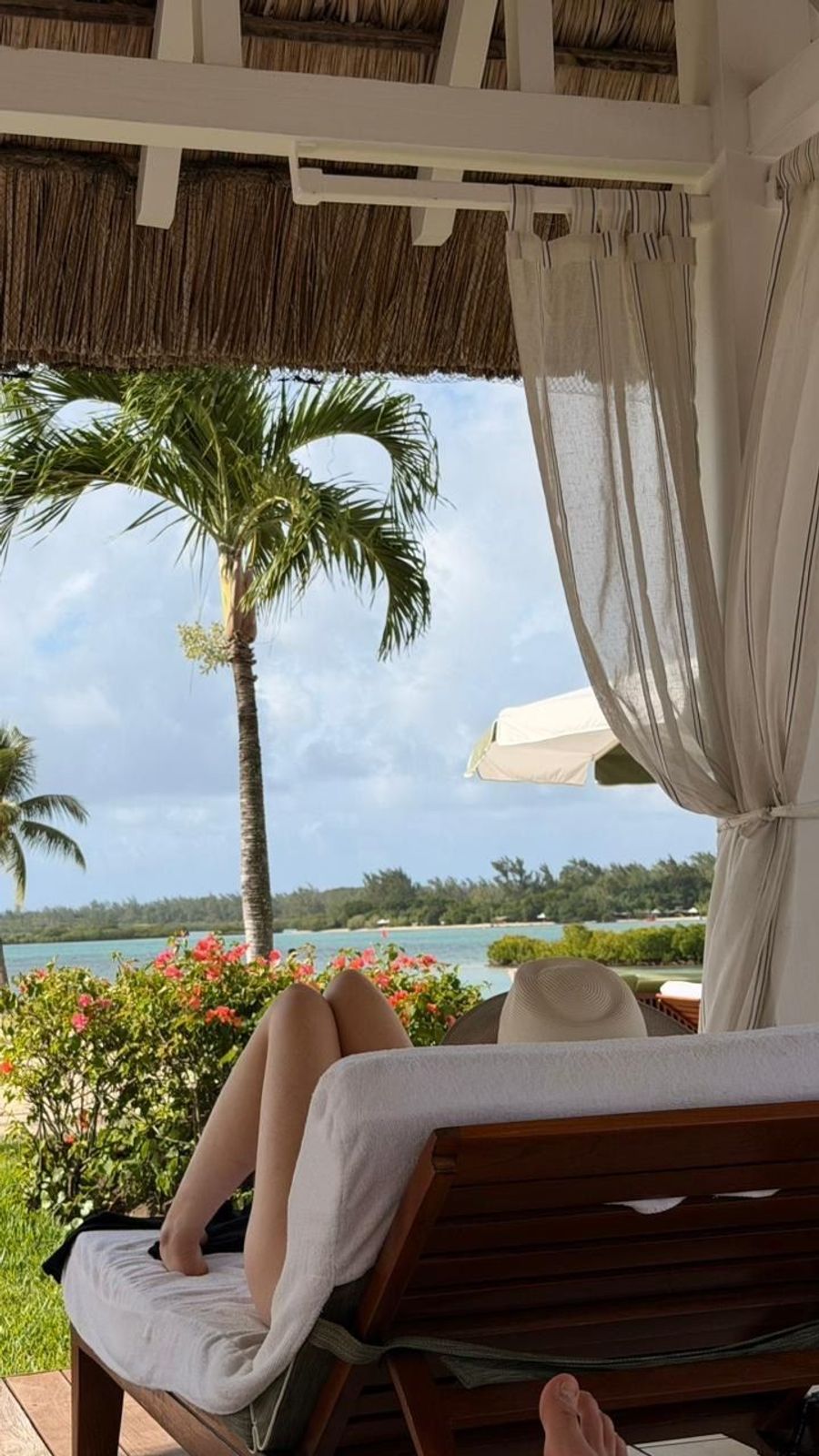 Sun-lounger view through a cabana drape with palm trees and the Anahita lagoon beyond, Four Seasons Mauritius