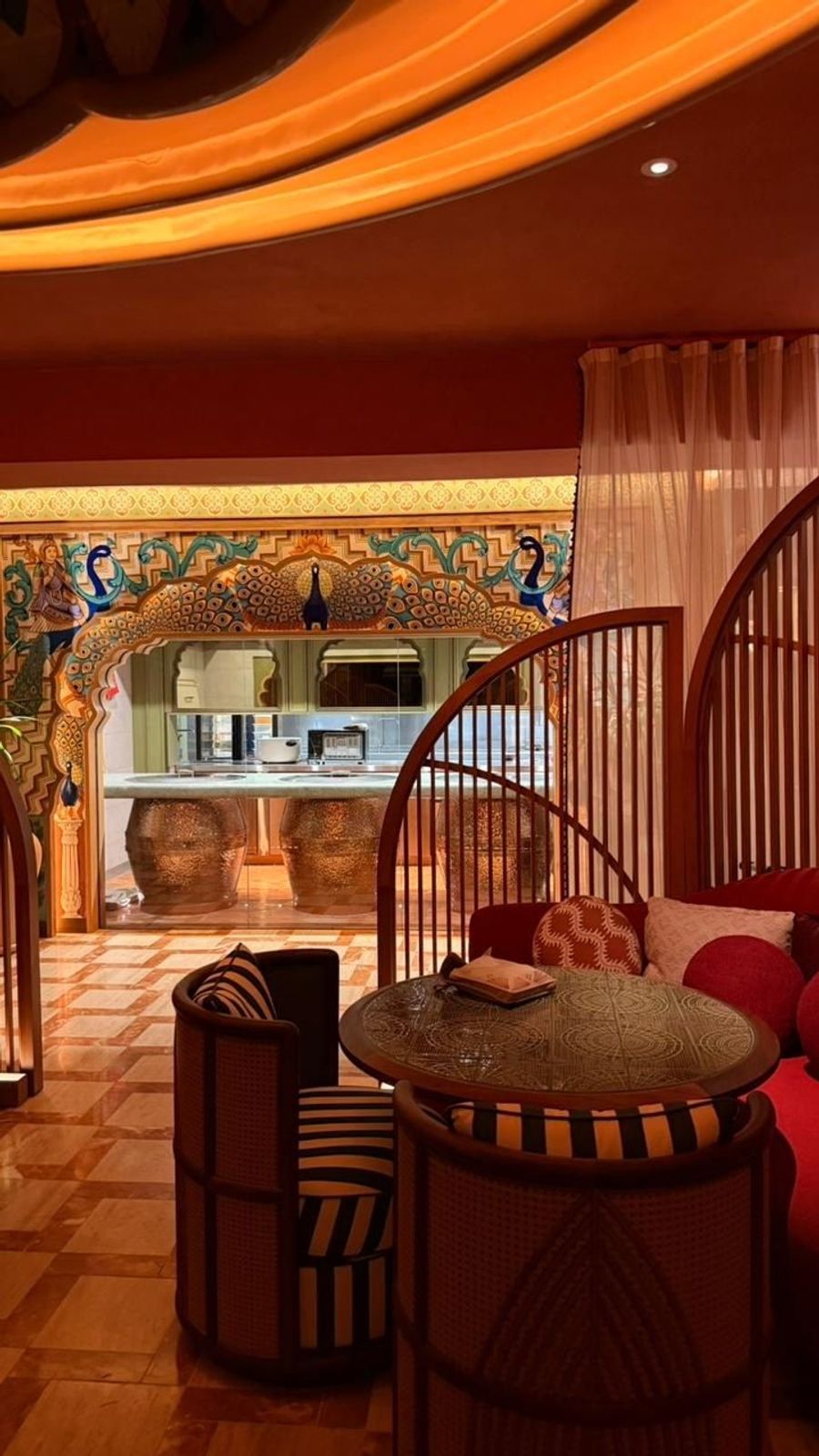 Warmly lit interior of Four Seasons' Indian restaurant at Anahita, with hand-painted arched entryway and woven seating, Mauritius